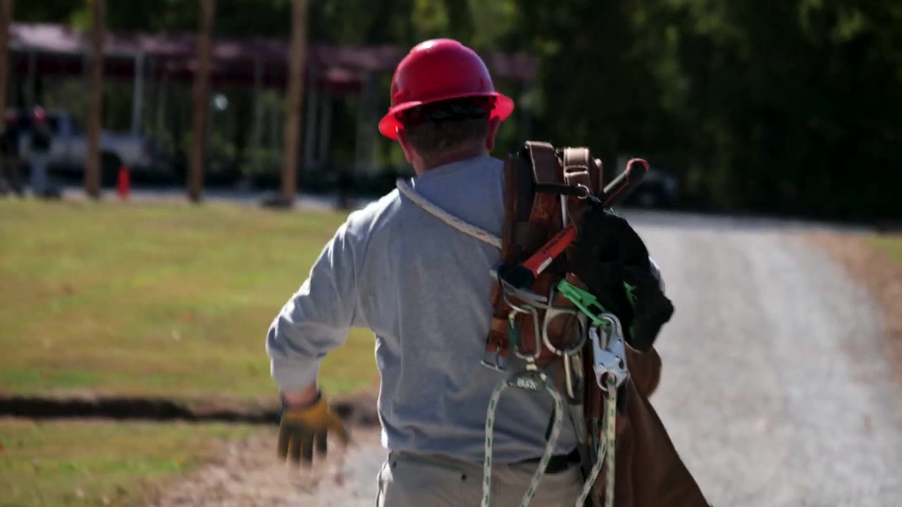 Lincoln Land Community College lineworker student carrying climbing equipment during a 55 North production