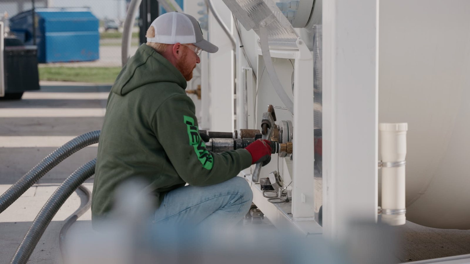 Team member connecting pump lines at Lenz Distributing storage tanks during operations filming