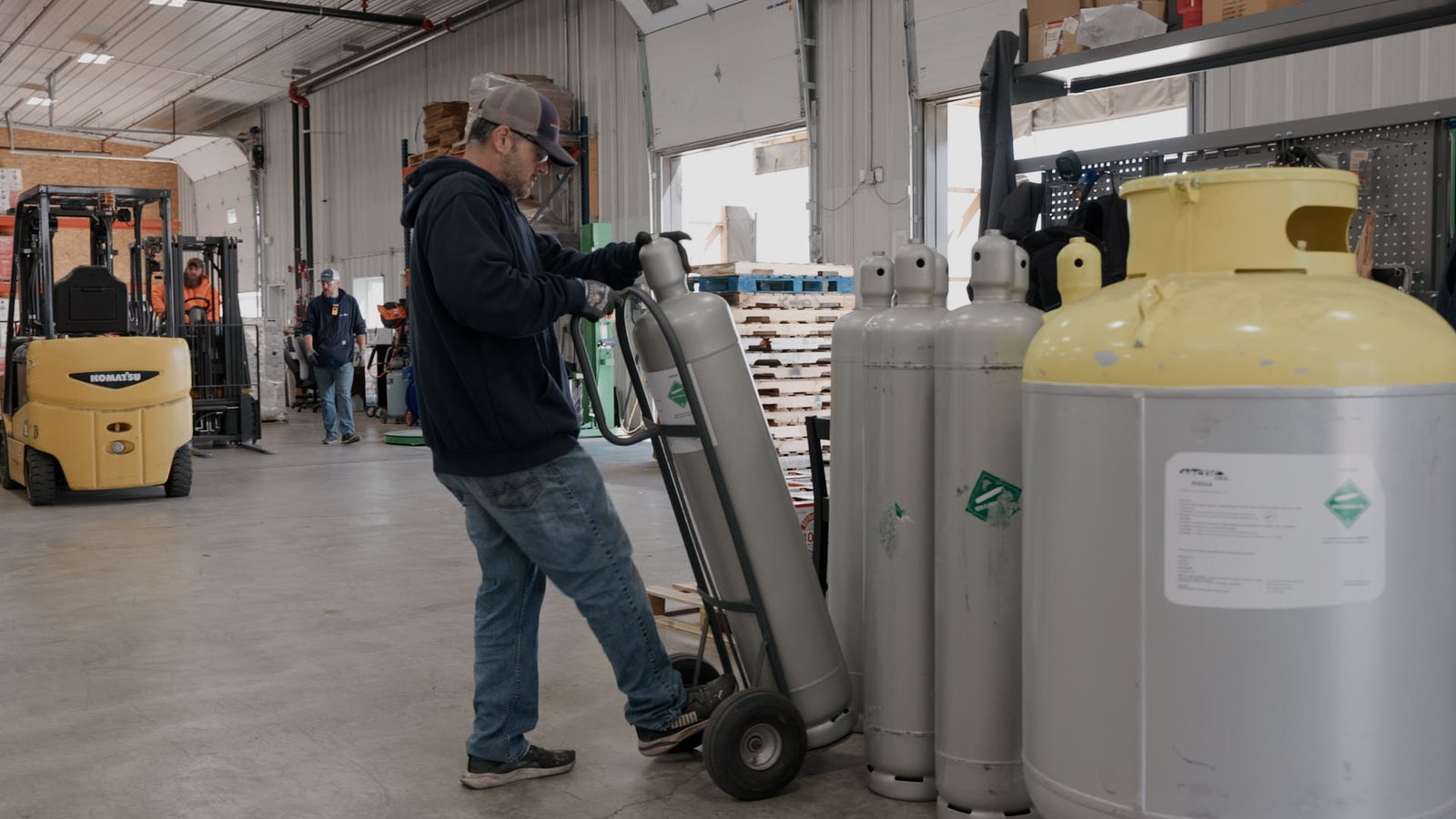 Lenz Distributing team member moving cylinders with a hand truck during operations video production